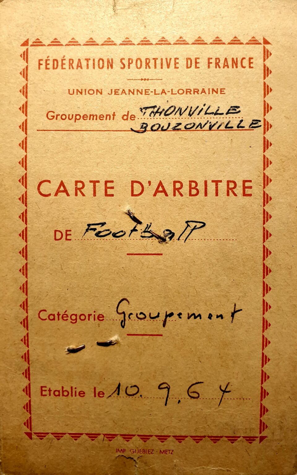 Une carte d'arbitre en carton, imprimée en rouge : « Fédération sportive de France — Union Jeanne-la-Lorraine », groupement de Thionville-Bouzonville, « CARTE D'ARBITRE de football », catégorie Groupement, établie le 10.9.64.